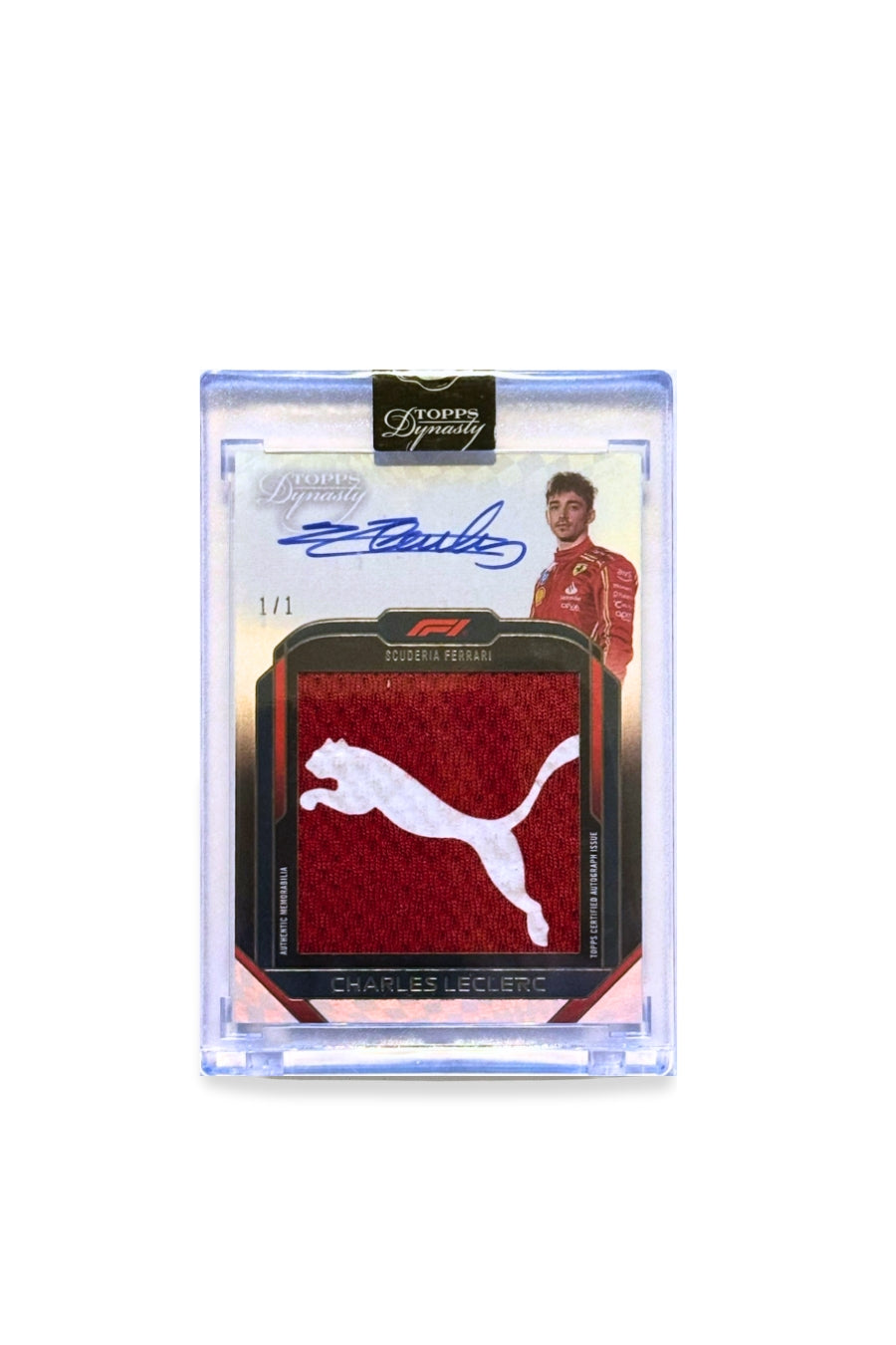 Front of 2024 Topps Dynasty Charles Leclerc Puma logo patch autograph F1 card, serial numbered 1 of 1, showing white Puma logo on red Ferrari fabric.